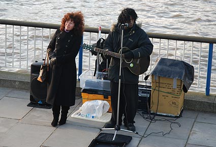 Woman poses for a picture next to busker, Hungerford Bridge, London, January, 2007