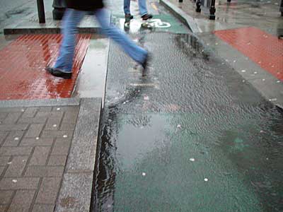 London rain, jumping over a puddle in Charing Cross Road, London
