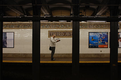 Reading the paper, Third Avenue subway station, Manhattan, New York, NYC, November 2006