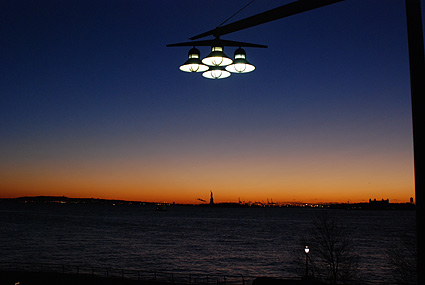 Lights over the Hudson with the Statue of Liberty in the distance. Night photographs on the streets of New York, NYC, December 2006