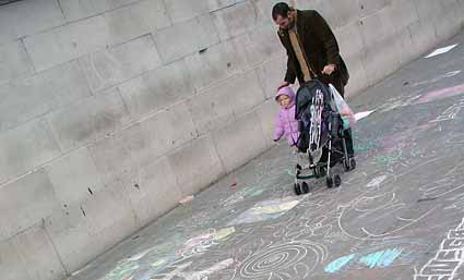 Dad with child walks over chalked pavement at the end of the protest, Trafalgar Square.
