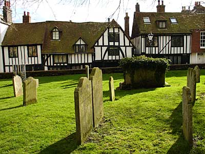 Sunlight and half timbered houses by the graveyard, The Parish Church of St Mary The Virgin, Rye, Sussex, UK