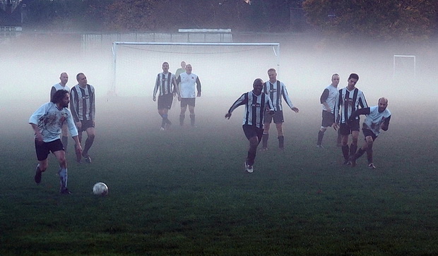Ghostly football - players hunt the ball in the swirling mists of Surrey