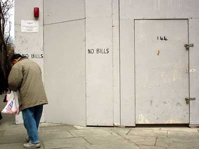 Boarded up shop and man.