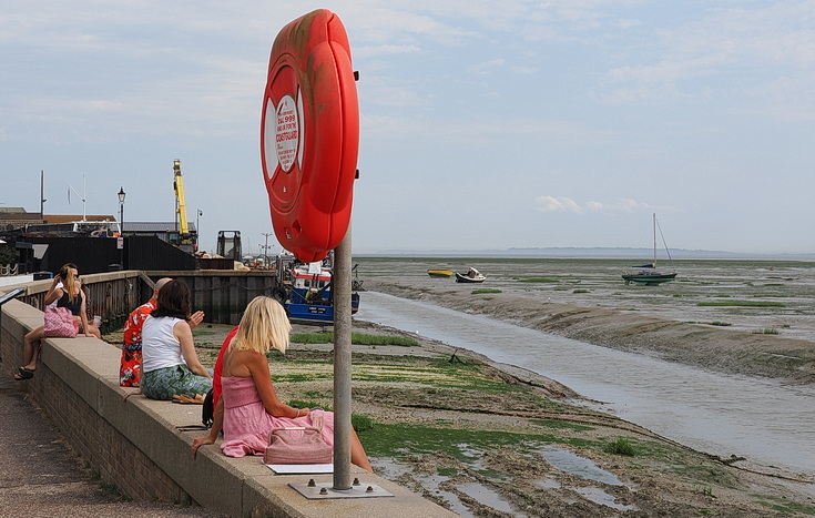 Swimmers and stranded boats on a sea of mud in the shadow of the oil refineries: Leigh on Sea in the summer 