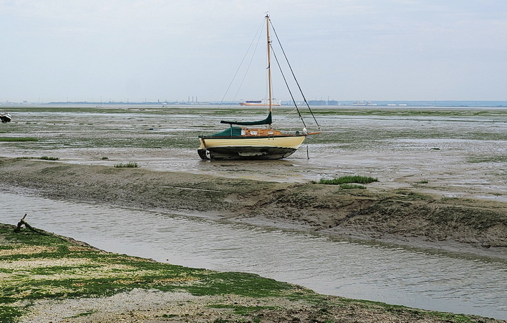 Swimmers and stranded boats on a sea of mud in the shadow of the oil refineries: Leigh on Sea in the summer 