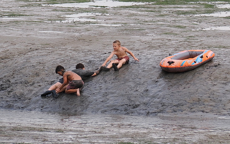 Swimmers and stranded boats on a sea of mud in the shadow of the oil refineries: Leigh on Sea in the summer 