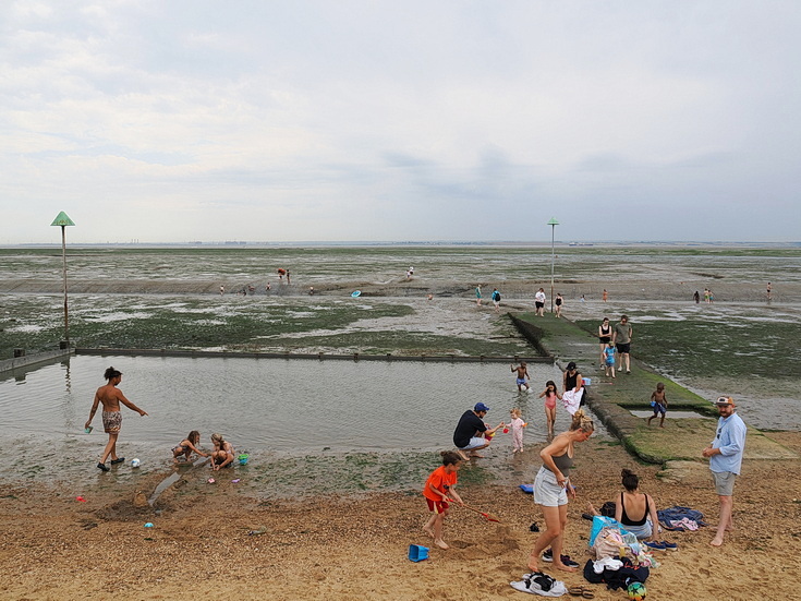 Swimmers and stranded boats on a sea of mud in the shadow of the oil refineries: Leigh on Sea in the summer 