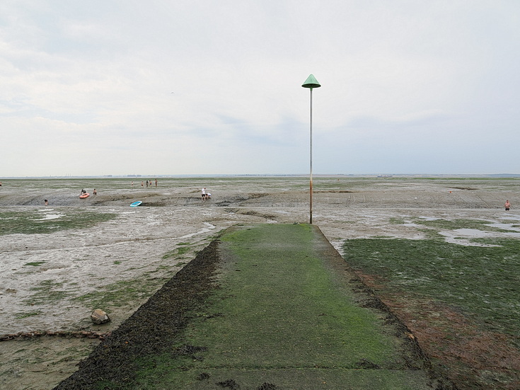 Swimmers and stranded boats on a sea of mud in the shadow of the oil refineries: Leigh on Sea in the summer 