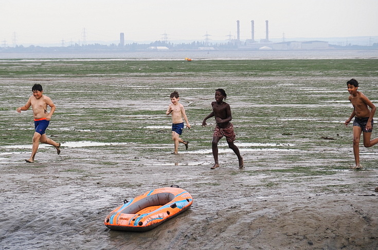 Swimmers and stranded boats on a sea of mud in the shadow of the oil refineries: Leigh on Sea in the summer 