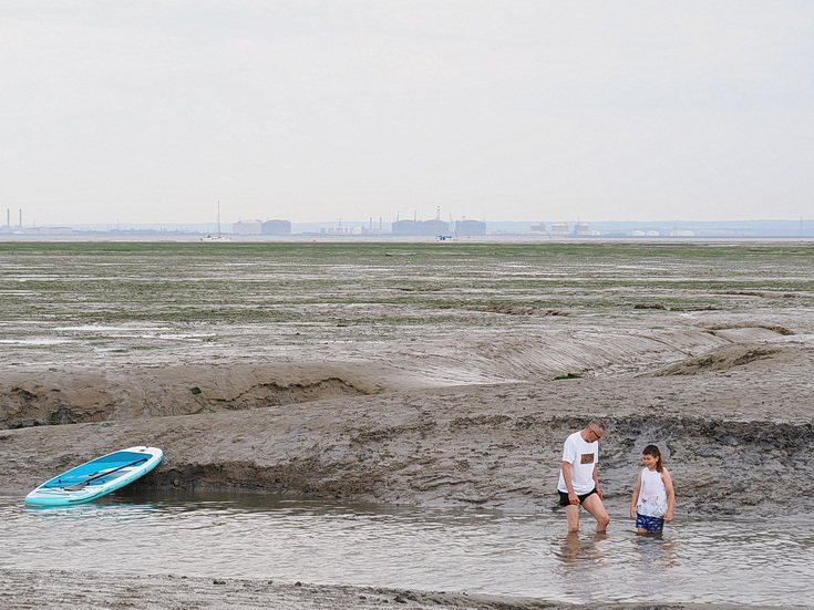 Swimmers and stranded boats on a sea of mud in the shadow of the oil refineries: Leigh on Sea in the summer 