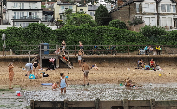 Swimmers and stranded boats on a sea of mud in the shadow of the oil refineries: Leigh on Sea in the summer 